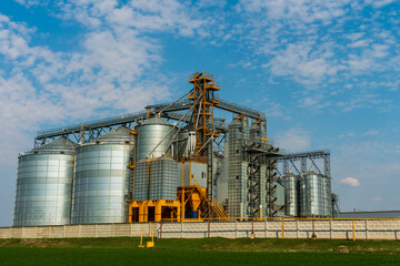 A large modern plant for the storage and processing of grain crops. view of the granary on a sunny day against the blue sky. End of harvest season. silver silos on agro manufacturing plant