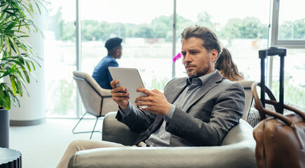 Handsome Businessman Using Digital Tablet While Waiting for his Flight in the Business Lounge