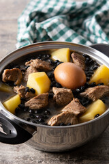 Traditional Jewish cholent in casserole on wooden table	