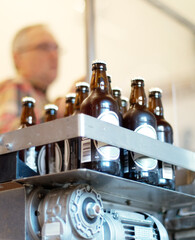 A delicious new brew. Shot of a batch of bottled beer in a brewery with an employee in the background.