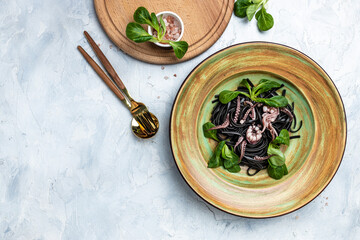 Squid ink spaghetti with seafood octopus, mussels and shrimps on light background. banner, menu, recipe place for text, top view