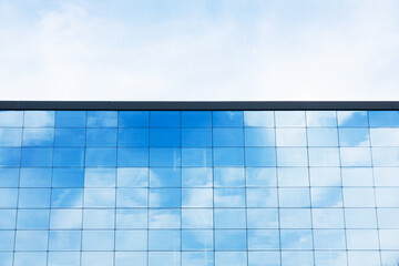 Office block texture. Glass skyscraper background. Glass window building. Blue, cloudy sky and sunlight.