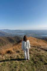 Naklejka na ściany i meble Traveler woman dressed in white on top of mountain admiring landscape of lago di como italy