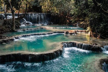 Amazing turquoise water of Kuang Si waterfall in tropical rain forest. Laos