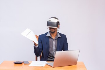 Man wearing virtual reality and working in office with a document file and laptop on his desk