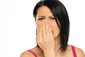 a middle aged woman checks her breath with her palm on a white