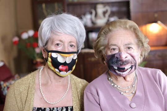 Senior Female Friends Wearing Hilarious Protective Masks