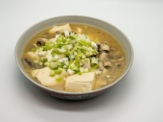 A bowl of shallot, tofu and mushroom soup