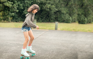 portrait of young child or teen girl roller skating outdoors, firness, wellbeing, active healthy...