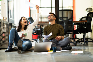 Colleagues in office. Businesswoman and businessman sitting on the floor. Colleagues working on the project