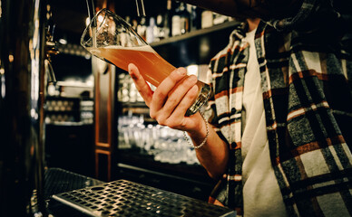 bartender pouring a draught beer in glass serving in a bar or pub