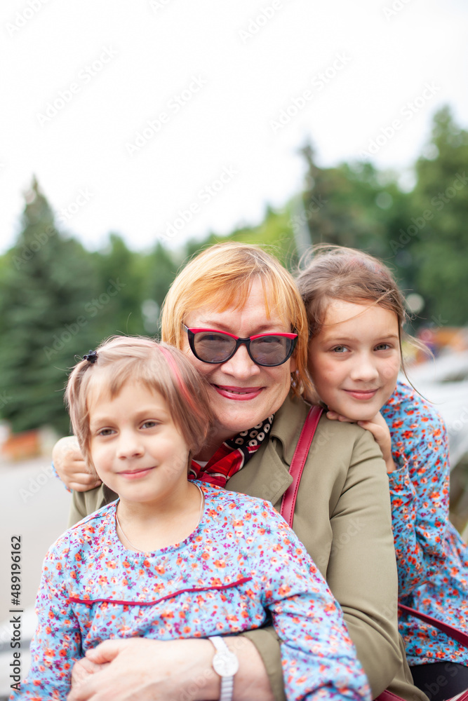 Sticker Old woman hugging  granddaughters at fountain in   park