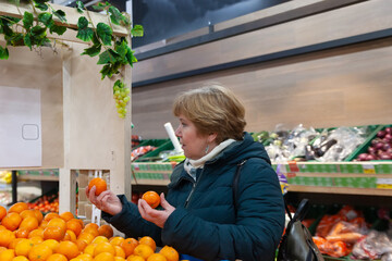 Smiling senior woman picking apple at the grocery shop