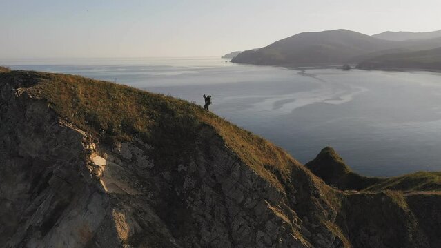 A man walking along a ridge with epic views of the mountains and the sea