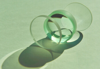Closeup of sunlight through clear circular convex and concave lens with different focus lengths overlapping. Mixture refection and refraction of light create artistic shade and shadow on white paper - obrazy, fototapety, plakaty
