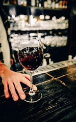 bartender hold red wine into a glass in cafe or bar