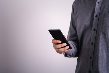 Close-up male hands using smartphone on gray empty space background. searching or social networks concept. online technology communication network.