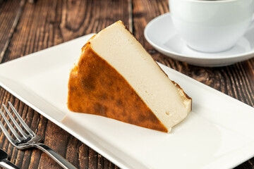 Fototapeta premium Sliced san sebastian cheesecake with coffee on wooden table