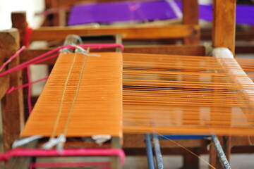 Colourful Thai silk yarn textile hand loomed in wooden weaving machine. Asian traditional cultural handmade silk