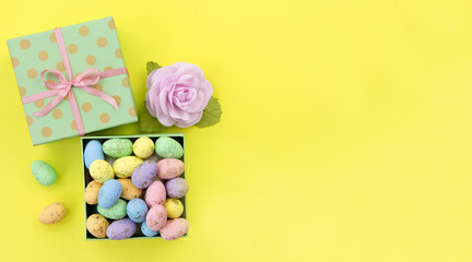 Colorful Easter eggs in a gift box on a yellow background. The concept of a holiday and shopping for Easter. Flat lay.Happy easter greeting card. Copy space