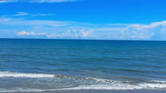 Deep blue ocean and sky reveals waves and beach