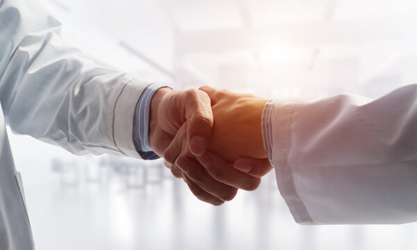 Close-up of the handshake between the two medics. Against the backdrop of the cityscape