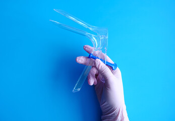 A hand in a pink rubber glove holds a gynecological mirror, a layout with copy space and space for...