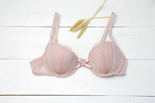 Women's light pink bra on white table. Female underwear background with copy space