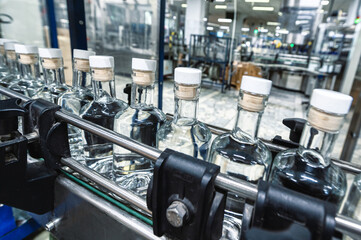 Closed bottles of expensive vodka transported by conveyor