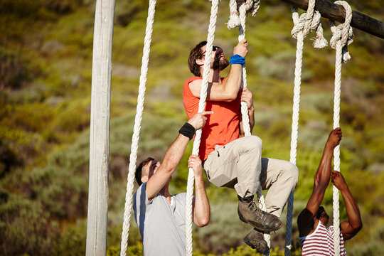 Boot Camp Is Rough, So You Gotta Be Tough. Shot Of A Group Of Men Climbing Up Ropes At A Military Bootcamp.