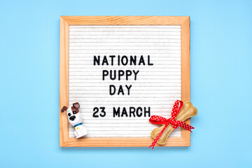 Felt board with text National puppy day in 23 march, cute dog figures, chewing bone with bow on blue background Top view Flat lay Holiday greeting card - 489206774