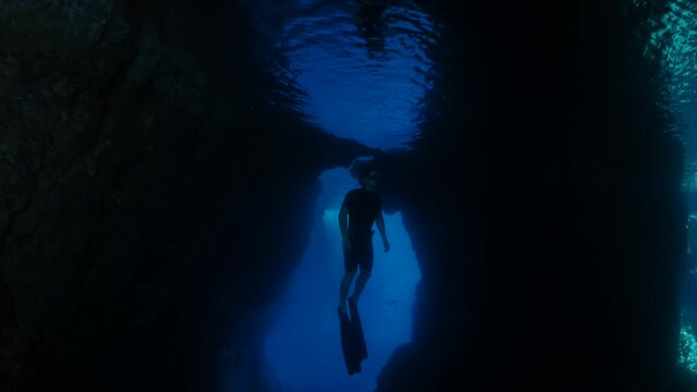 freediver apnea man free diving in a cave underwater with nice lightning ocean scenery