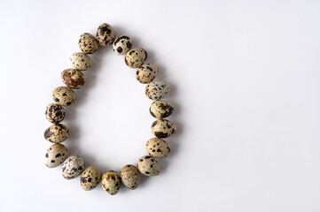 quail eggs are stacked in one large egg on a white background. Top view. Copy space