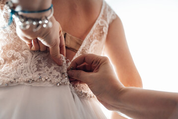 A closeup shot of female hands zipping up the wedding dress on a bride