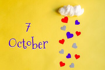 7 october day of month, colorful hearts rain from a white cotton cloud on a yellow background. Valentine's day, love and wedding concept