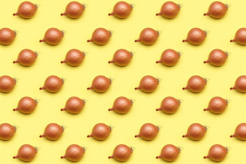 Onion head in a golden yellow peel on a yellow background. Pattern, template, background, studio shot.
