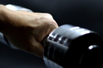 Hand holding a dumbbell with a black background