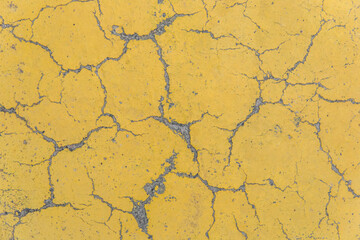 Cracks on yellow paint concrete surface cracked weathered cement worn texture broken abstract damaged pattern background