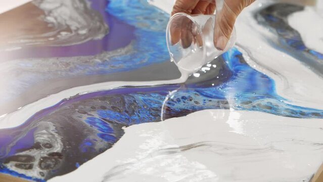 Epoxy design - pouring white epoxy resin on the painting surface