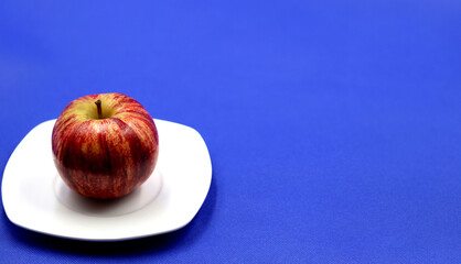 Red apple on blue background for copy space