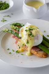 Close up of eggs benedict topped with chives and hollandaise sauce. 