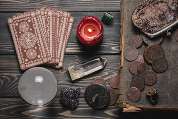 Tarot cards, crystal ball and magic book on the old wooden fortune teller table flat lay...