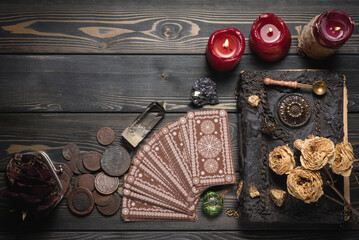 Tarot cards and magic book on the old wooden fortune teller table background with copy space....