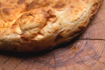 Close-up fried khachapuri cooked in the oven lies on a wooden board