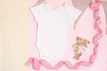Easter mockup baby bodysuit with bunny and easter eggs on pink cover background. Flat lay, top...