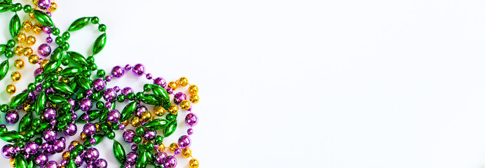 Mardi Gras background. Gold, green and purple beads on white background. Fat Tuesday symbol.