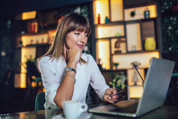 Young woman sitting in cafeteria and perform online shopping