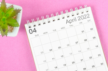 April 2022 desk calendar with plant pot on pink background.