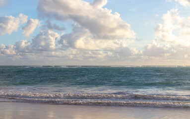 Idyllic seascape, white clouds above the sea. Ocean horizon. Waves and sand beach.