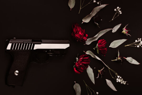 Flat lay for the world, on a black background gun and rose flowers, simulating a shot